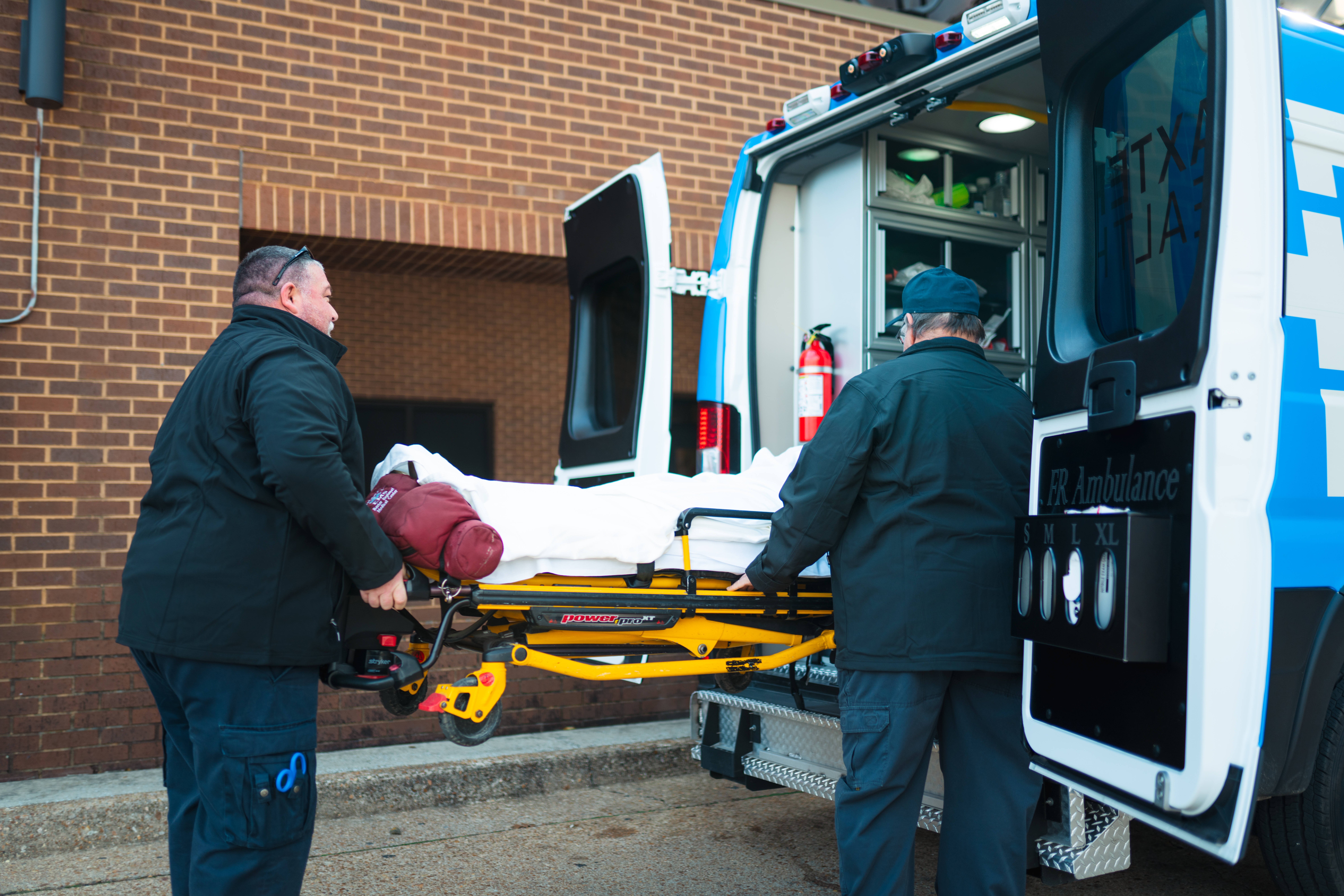 Emergency Medical Vehicle being unloaded by two male emergency service members